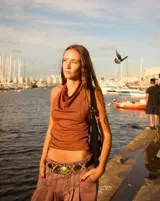 Cartera baguette color naranja con correa corta para llevar al hombro. Decorada con tachas, botones y dijes.