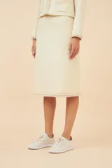 Falda midi de lana color gris con textura tweed y corte recto. Presenta un galón tejido marrón en el ruedo y forro al tono.