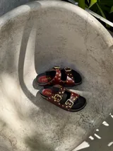 Sandalia marrón de cuero vacuno con detalle de tachas doradas en la capellada, plantilla birk forrada en cuero y fondo negro de eva.