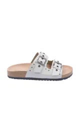 Sandalias bajas color blanco con dos tiras anchas con hebillas plateadas y tachas pequeñas. Suela de corcho.
