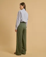 Pantalón de lino verde con rayas verticales negras y blancas, de tiro alto, corte palazzo y bolsillos laterales.