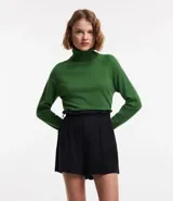 Blusa de punto color blanco, con cuello alto, manga larga y diseño liso.