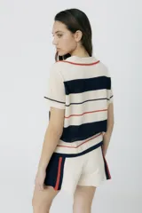 Remera polo tejida a rayas horizontales rojas y rosadas, con cuello clásico y bordado de ají verde.