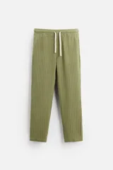 Pantalón verde oliva de corte relaxed fit, confeccionado en tejido de algodón con textura. Tiene cintura elástica ajustable con cordón, bolsillos frontales y un bolsillo trasero de parche.