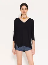 Remera negra de punto liviano con escote en V, mangas 3/4 y recortes diagonales en el delantero.