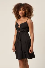 Vestido corto color verde claro, con tirantes finos, detalle de lazo en el escote y falda con volantes escalonados.