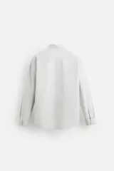 Camisa celeste de corte slim fit, confeccionada en tejido de algodón. Tiene cuello italiano, mangas largas con puños abotonados y cierre frontal con botones.