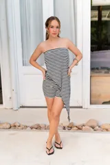 Conjunto de dos piezas color beige claro, compuesto por un top strapless con bajo asimétrico y un pantalón ancho de tiro alto.