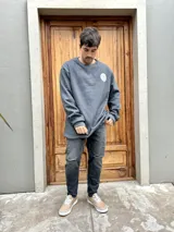 Buzo gris con cuello redondo y logo estampado en el pecho. Corte oversize.