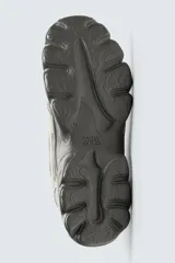 Zapatillas deportivas color crema con cordones, suela gruesa con diseño irregular y detalles en gris.