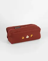 Neceser rectangular de tela color ladrillo con cierre superior y tres bordados pequeños: una hoja de arce, una taza de té y un croissant.