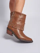 Bota de cuero color marrón con caña media, taco cuadrado y punta fina. Presenta tachas plateadas en el borde superior y en la tira que rodea el tobillo. El cuero tiene un acabado liso y brillante.