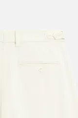 Pantalón de vestir color crema, de corte recto, con bolsillos laterales y traseros de ojal con botón.
