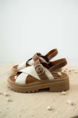 Sandalias bajas color marrón de cuero gamuzado, con tiras cruzadas y hebilla metálica.