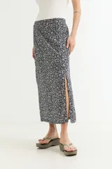 Falda midi fluida, color negro con estampado floral pequeño en blanco. Presenta un talle alto y una abertura lateral pronunciada.