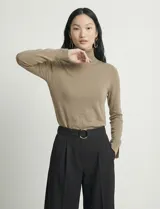 Polera de punto fino marca Nienty, color blanco, con cuello alto volcado y mangas largas con detalle de tajo en los puños.