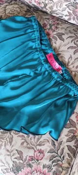 Mini culotte color verde esmeralda confeccionado en satén dull, con cintura elástica y terminaciones con puntilla negra.