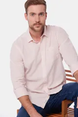 Camisa de lino color beige, de manga larga, con cuello clásico y bolsillo en el pecho.
