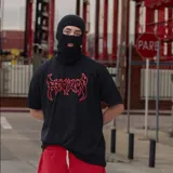Remera negra de algodón con estampado frontal de letras rojas con estilo de banda de metal.