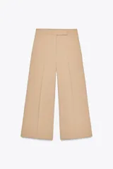 Pantalón culotte color beige de tiro alto con bolsillos delanteros y falsos bolsillos de vivo en la espalda. Pierna ancha y corta. Cierre frontal con cremallera, botón interior y gancho.