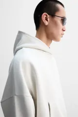 Sudadera color crudo, estilo hoodie, corte boxy, con capucha, manga larga, bolsillo tipo canguro y terminaciones en rib.