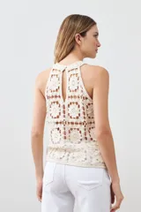Top tejido crochet color crudo, con cuello halter y espalda descubierta.