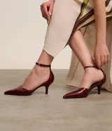 Zapato de tacón color marrón con punta fina, tira fina con hebilla lateral para cierre y tacón fino.
