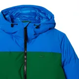 Campera puffer Lacoste con capucha, color block en azul, verde y marrón. Tiene cierre frontal con cremallera, bolsillos laterales con cremallera y logo de la marca bordado en el pecho.