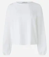 Blusa color lila confeccionada en crepé, con escote redondo y mangas largas con puños elásticos.