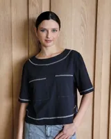 Remera negra con cuello redondo y mangas cortas, con detalle de pespuntes blancos en cuello, mangas, bolsillos frontales y ruedo.