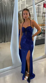 Vestido largo de fiesta color azul con acabado brillante. Diseño entallado con tirantes finos, escote corazón con abertura central y falda con tajo lateral profundo.