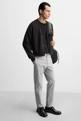 Pantalón negro de corte slim fit, confeccionado en tejido elástico. Cuenta con cintura elástica, bolsillos frontales y traseros de vivo. Cierre frontal con cremallera y botón.