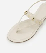 Sandalia marrón de cuero sintético, con tiras finas, apliques de conchas doradas y cierre con hebilla.