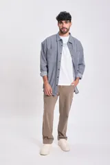 Sobrecamisa de hombre de jean, color azul, con patrón de rayas verticales finas. Presenta cuello camisero, bolsillos frontales con tapa y botones oscuros. Se lleva abierta sobre una remera blanca.