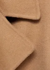 Abrigo largo color camel, con cuello con solapas, manga larga, cinturón desmontable y bolsillos laterales.