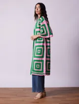 Cardigan largo tejido al crochet con diseño geométrico en verde y rosa. Tiene mangas 3/4 y corte holgado.