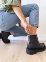 Bota negra con detalle de textura y cierre lateral, de suela gruesa y diseño moderno.