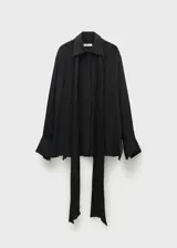 Camisa negra de tejido fluido semitransparente, con cuello camisero, lazo en el cuello, manga larga con puños abotonados, diseño recto, bajo con aberturas laterales y cierre delantero con botones.