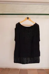 Chaleco negro tejido a mano en dos agujas con hilado 100% baby alpaca, ligeramente oversize, de hombros anchos y cuello tipo bote, con puntos calados en frente y espalda y tajos a los lados en el bajo.