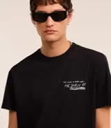 Remera negra de algodón con corte comfort, cuello redondo y mangas cortas. Estampa frontal con ángel y lettering en blanco.