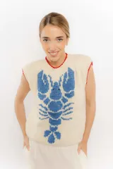 Chaleco tejido color crema con diseño de langosta azul y detalles en rojo en cuello y ruedo.