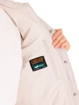 Campera color rosa pálido con diseño acolchado en forma de hojas, cuello camisero, cierre frontal con botones a presión, dos bolsillos de parche en el pecho y corte recto.