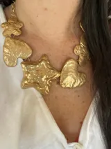 Collar dorado con cadena y dijes colgantes con formas de corazón, estrella y flor.