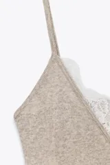 Top color beige de breteles finos con escote en V y detalles de encaje blanco en el escote y el ruedo.