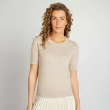 Sweater de punto color beige de manga corta y cuello redondo.