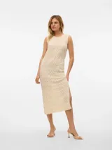 Vestido midi de punto color crema, sin mangas y con cuello redondo. Presenta un diseño calado con motivos geométricos y una abertura lateral en la falda.