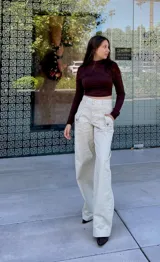 Pantalón de jean color nude, de corte recto y tiro alto, con bolsillos laterales y traseros.