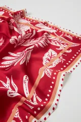 Pañuelo cuadrado rojo con estampado floral blanco y borde con diseño de puntos.