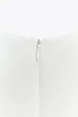 Top blanco sin mangas, con cuello halter y bajo con pliegues. Cierre trasero con cremallera oculta.