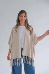 Ruana color beige de tejido de punto con flecos en el ruedo.